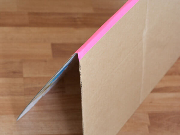 Bước 6 cách làm ngôi nhà bằng giấy carton - Bạn dán băng dính màu hoặc giấy bìa màu cố định hai miếng bìa bạn vừa cắt ở bước 5 để tạo thành phần mái nhà như hình